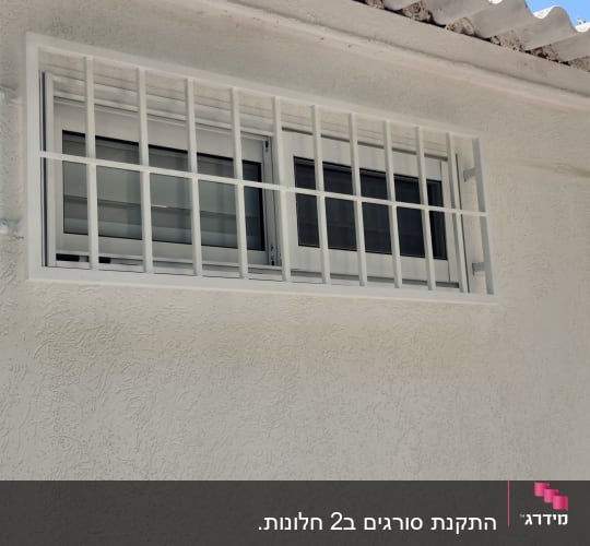 חלון עם סורגים על קיר חיצוני לבן